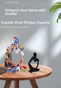 Close-up of abstract thinker sculptures in black matte and pop art print on wooden table