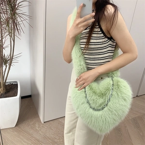 Detail of mint green plush heart bag featuring a silver metal chain and soft furry texture
