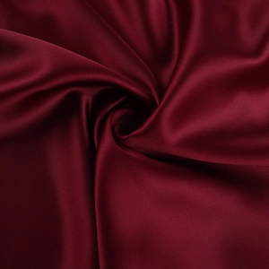 Macro detail of glossy burgundy satin fabric showing smooth texture and elegant drape