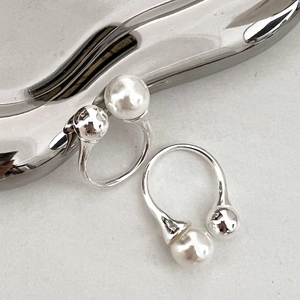 Detail eines silbernen U-Ohrrings mit weißer Perle und polierter Metallkugel-Akzenten