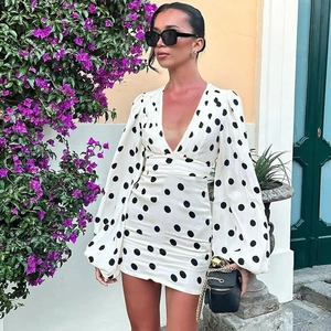 Dettaglio dello scollo a V profondo e dell'elegante stampa a pois sul vestito bianco