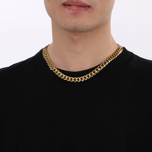 Chaîne cubaine dorée polie pour homme portée au cou avec un t-shirt noir sobre