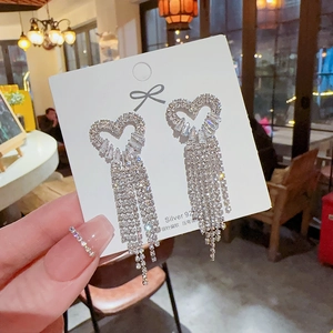 Detail shot of heart-shaped tassel earrings with sparkling zircons on a display card