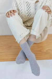 Close-up of grey coral fleece socks on feet showing soft plush texture and thick warmth