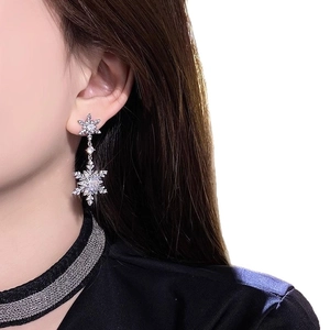 Sparkling silver snowflake drop earrings with zircon crystals on a female model