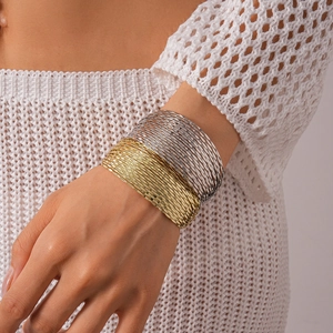 Close-up of layered geometric gold and silver metallic bangles worn by a model