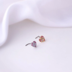 Macro shot of L-shaped heart nose studs with pink and purple zircon in gold and silver