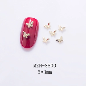 Macro shot of 5x3mm golden 3D hollow butterfly nail charms on a red glossy nail