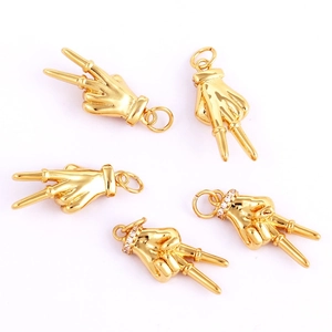 Close-up of golden copper victory hand pendants with micro-pave sparkling crystals