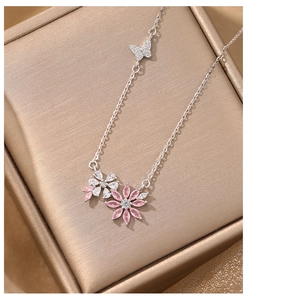 Detailed close-up of pink and white zircon flower pendant with butterfly on a jewelry box