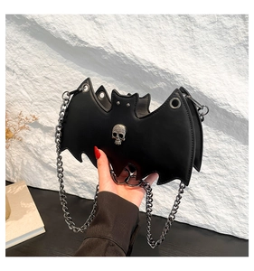 Detail of gothic bat-shaped crossbody bag with metallic skull and silver chain strap