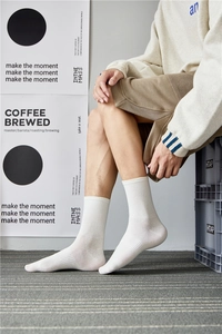 Close-up of white mid-calf cotton socks worn by a model in a lifestyle setting