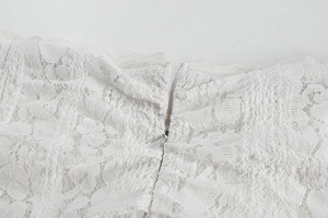 Close-up of intricate white floral lace dress with high-quality invisible back zipper detail