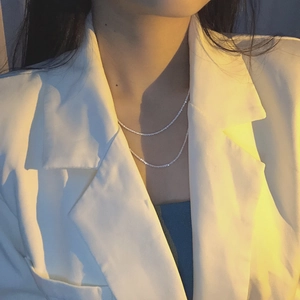 Close-up of double-layered silver clavicle necklace on a model wearing a blazer