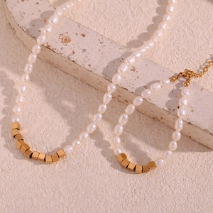 Detail of freshwater pearl necklace with gold square beads on light stone surface