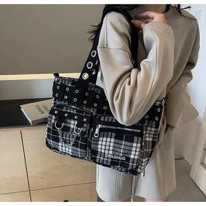 Detail of checkered tote bag featuring silver metal eyelets and a decorative chain link