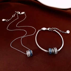Detail of silver necklace and bracelet set with blue gems on red velvet background