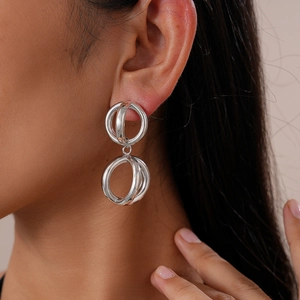 Close-up of geometric double circle silver earrings on model showing glossy metallic finish