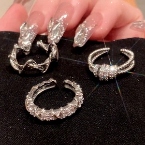 Geometric silver rings set with sparkling zircons on black fabric background