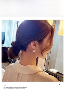 Detailed close-up of a pearl drop earring in gold finish worn by a female model
