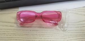 Detailed view of pink translucent square sunglasses in a clear protective plastic bag