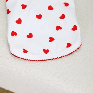 Detail of red heart print on white fabric with wavy red lace trim for dog clothing
