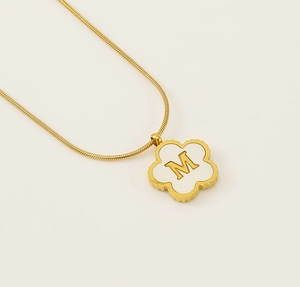 Close-up of 18K gold-plated clover pendant with white shell inlay and letter M engraving