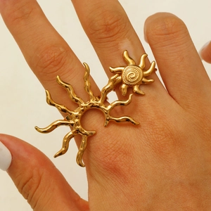 Close-up of golden sun-shaped textured ring worn on model hand in a minimalist setting