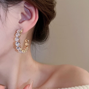 Close-up of gold C-shaped hoop earrings with sparkling cubic zirconia on model