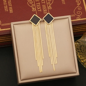 Detail of long gold tassel earrings with black square stud on jewelry display box