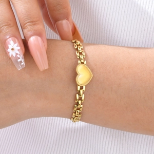 Dettaglio del ciondolo a cuore dorato su bracciale a catena piatta indossato al polso