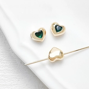 Macro detail of 18k gold plated heart beads with green zircon for DIY jewelry making