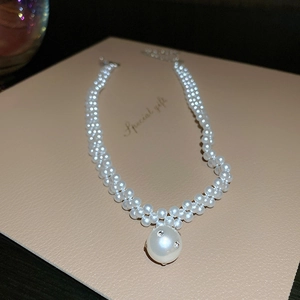 Double-layered pearl necklace featuring a large rhinestone-encrusted pearl pendant