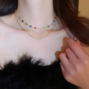 Close-up of double-layer choker with colorful gemstones and gold rope chain on neck