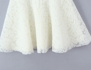 Vue macro détaillée de la broderie en dentelle florale blanche sur l'ourlet de la robe