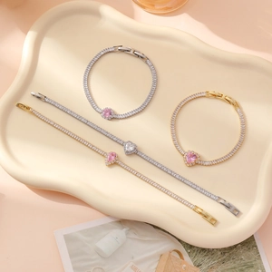 Sparkling zircon heart bracelets in gold and silver finish on a cream display tray