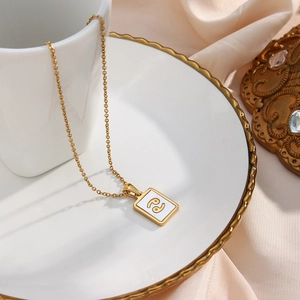 Detailed view of Cancer zodiac shell pendant necklace on a decorative gold-rimmed white plate