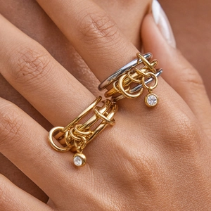 Macro view of layered titanium steel rings with round zircon charms on model's fingers