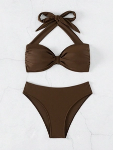 Detalle de bikini marrón oscuro con top halter de lazo y braga de talle alto sobre mármol