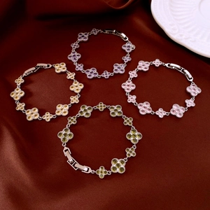 Detailed view of clover charm bracelets in purple, pink, and green zircon on silk