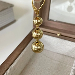 Close-up of golden triple ball earrings on a jewelry box featuring minimalist sphere design