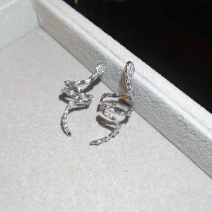 Macro shot of silver snake earrings with white zircons on a gray velvet jewelry box display