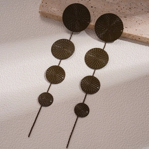 Detailed macro view of long drop earrings with five layered textured spiral metal discs