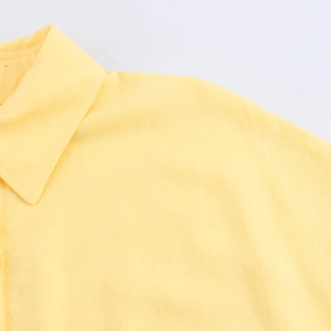 Detail of yellow linen shirt collar and shoulder seams with natural fabric texture