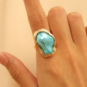 Nahaufnahme eines goldenen Barockrings mit einem einzigartigen blauen Edelstein am Finger