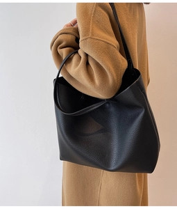 Minimalist black pebbled leather tote bag shown on a model for size and scale