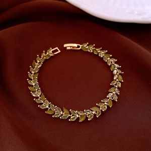 Detail of zircon wheat ear bracelet with olive green stones on a brown velvet surface