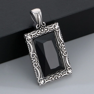 Détail macro du pendentif vintage argenté avec pierre noire facettée et gravure florale