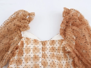 Dettaglio abito in tulle con motivi floreali 3D, pois neri e spalline con volant