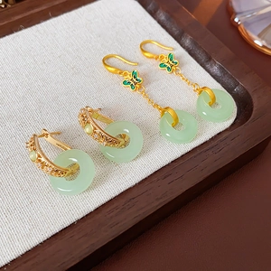 Vue détaillée de boucles d'oreilles papillon en or 18K et jade sur plateau en bois